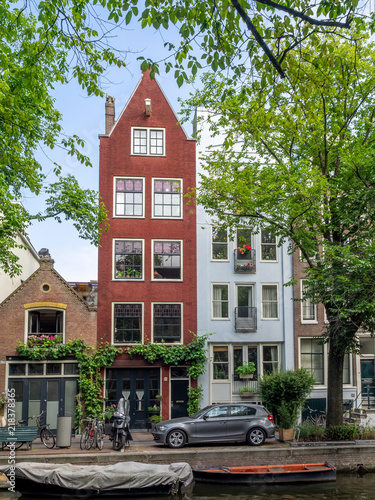 Amsterdam canal, bridge and typical houses, boats and bicycles during the day, Holland, Netherlands.