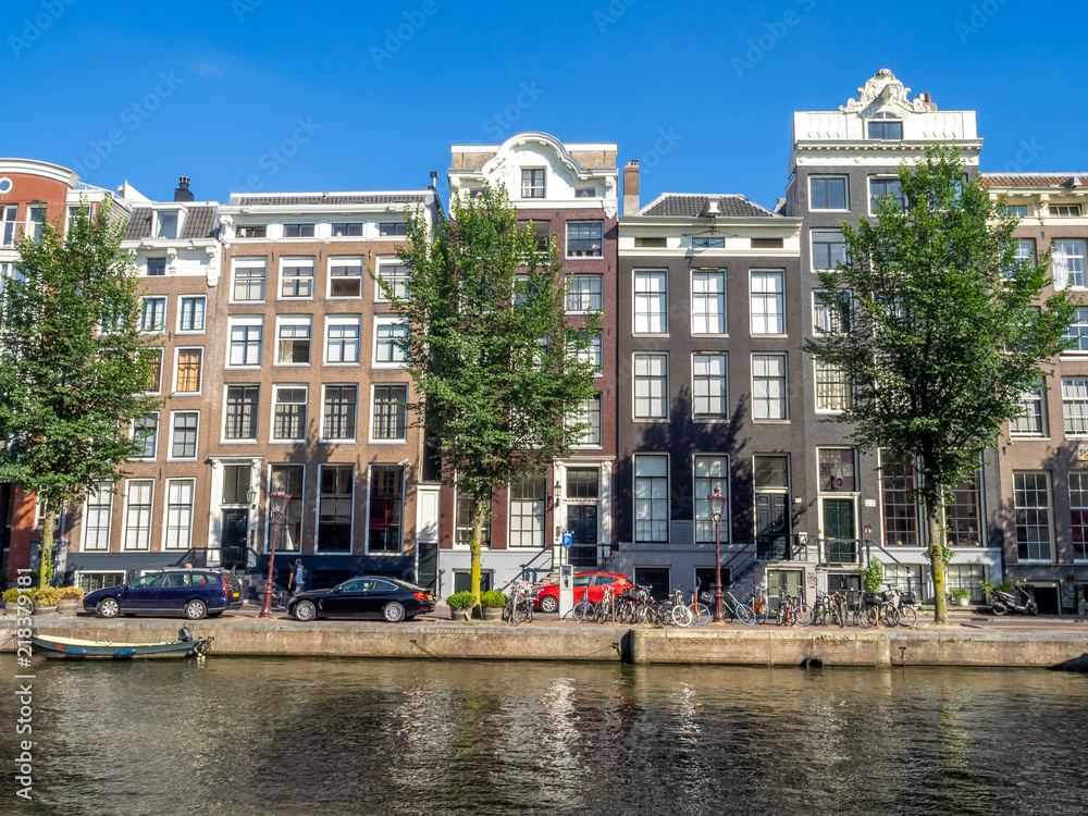 Amsterdam canal, bridge and typical houses, boats and bicycles during the day, Holland, Netherlands.