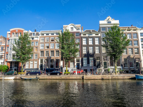 Amsterdam canal, bridge and typical houses, boats and bicycles during the day, Holland, Netherlands.
