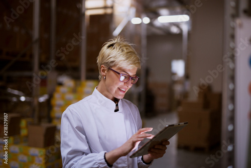 Young female manager is using tablet in storage room of a factory.