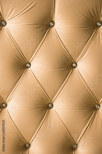 Beige soft textile background with symmetrical buttons on the corners of diamonds. Soft and expensive furniture elements. Luxury background