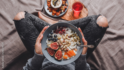 Valokuva Woman eating Rice coconut porridge with figs, berries, nuts and coconut milk in plate