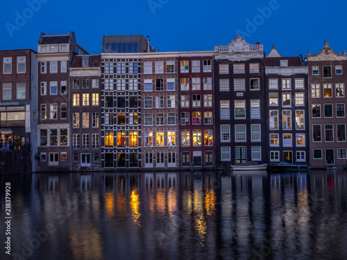 Historic buildings on the Damrak canal in the centre of beautiful Amsterdam at night.