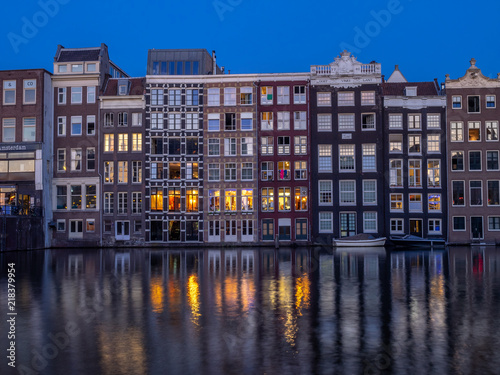 Historic buildings on the Damrak canal in the centre of beautiful Amsterdam at night.