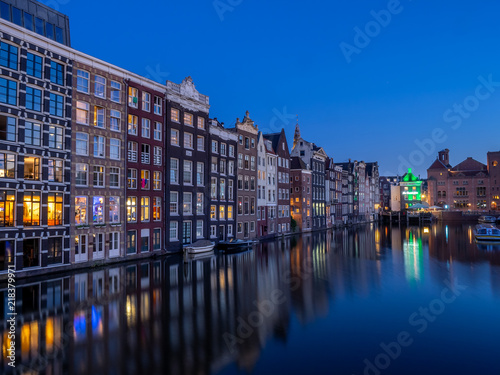 Historic buildings on the Damrak canal in the centre of beautiful Amsterdam at night.