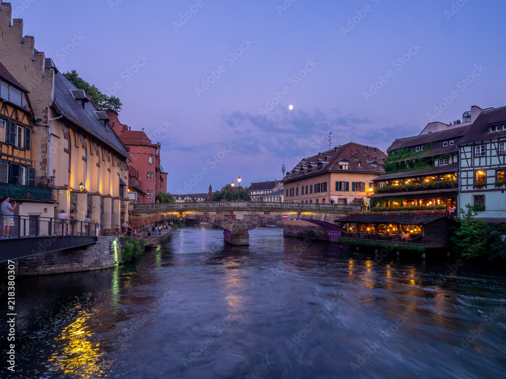 Fototapeta premium Sunset along the Ill River in Petite France areas of Strasbourg in the Alsace region of France. The homes are the traditional half timbered houses visible all over this area of France.