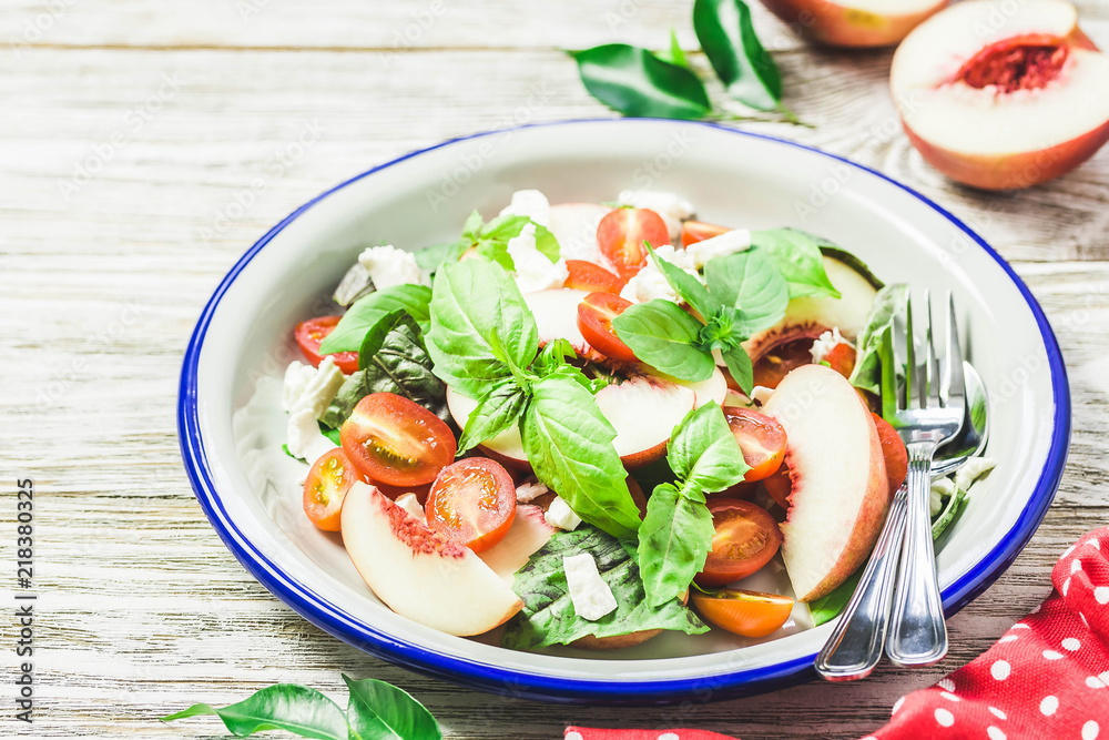 Peach tomato basil salad on white rustic background. Top view, space for text. Peach tomato basil salad on white rustic background. Top view, space for text.