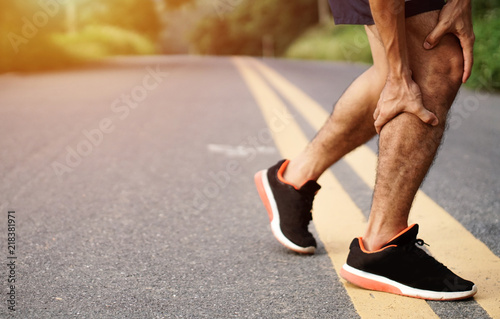 Sport injury. Accident concept,Young fitness man holding his sports leg injury, after running and exercise outside in summer.