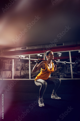 Close up of a young strong fitness female model doing squats with weight. © dusanpetkovic1