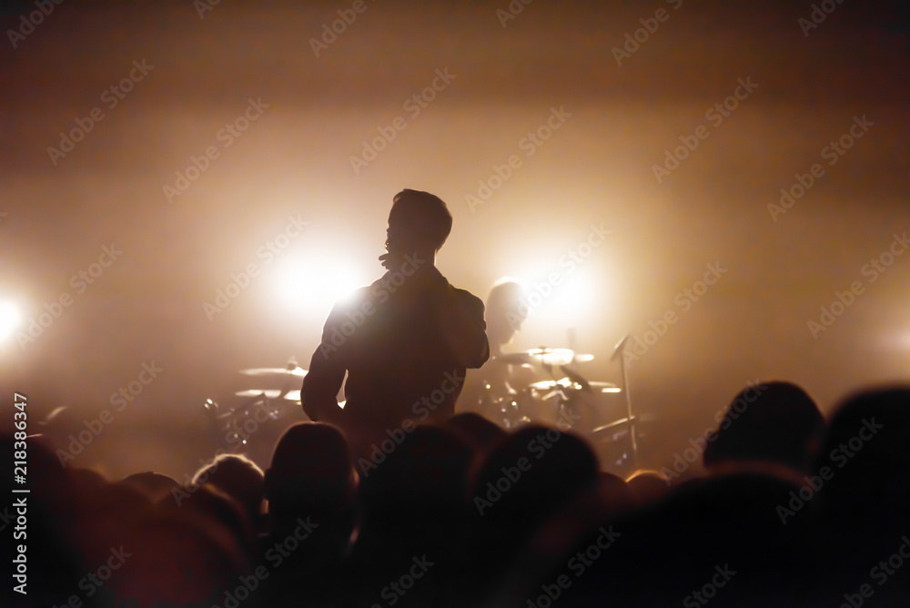 the silhouette of a vocalist and a drummer on the stage of a musical rock festival. audience at the concert. concert photo of musicians.