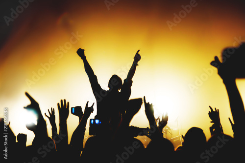 silhouette of a singer performing on stage at a concert among rock fans. the crowd takes pictures of the concert on the phone. concert photo among the spotlights.