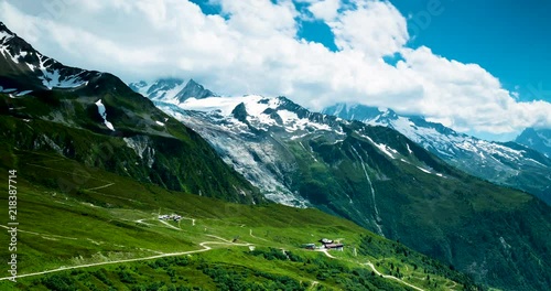 footage of the mont blanc massif near chamonix in the french alps showing clouds moving against blue summer sky and green alpine meadows
