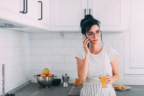 Beautiful young girl talking on a cellphone in the kitchen
