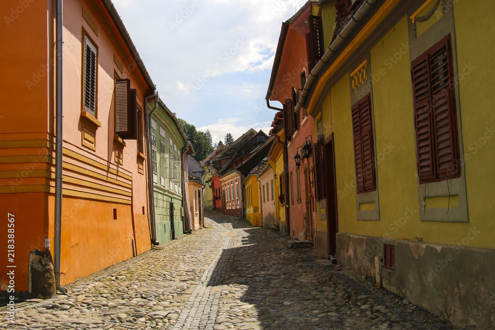 Stone paved old streets with colorful houses in Sighisoara, Romania.