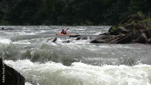 static shot of rushing water and passing kayaker