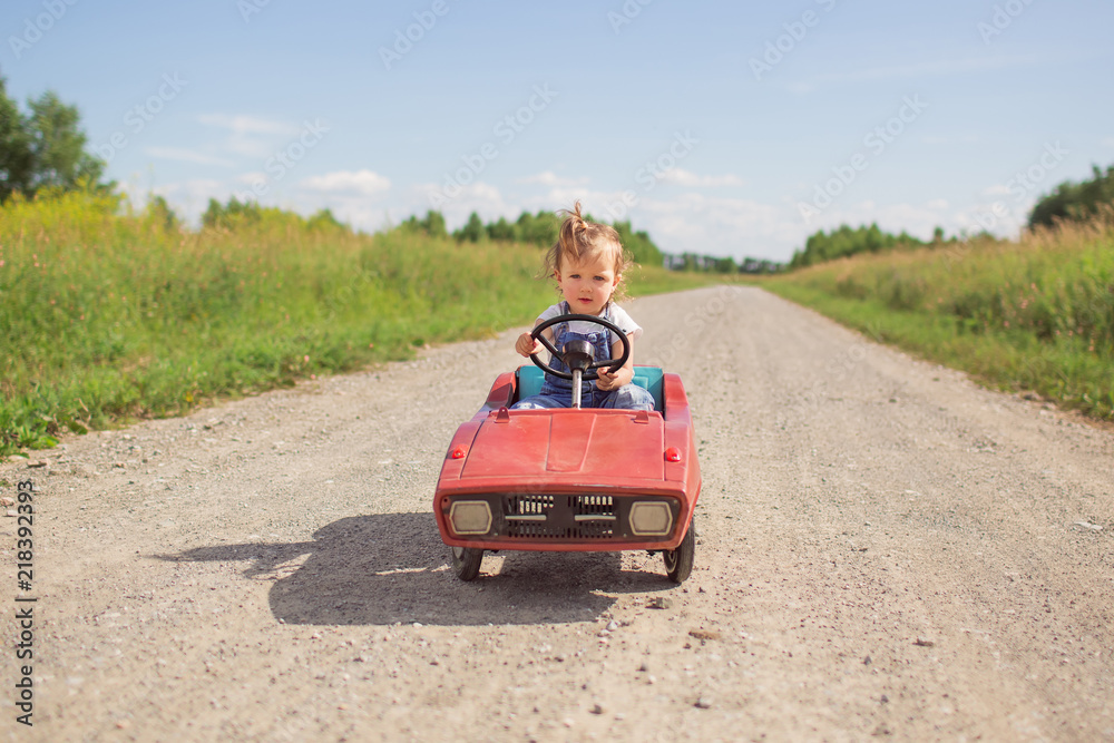 A little girl is driving along the road on a children's typewriter. A little girl is driving along the road on a children's typewriter.