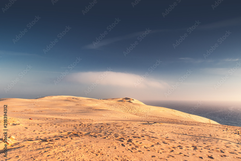 Endless sand dunes and ocean shore with blue sky and moody cloud mist. Rubjerg Knude Lighthouse, Lønstrup in North Jutland in Denmark, Skagerrak, North Sea