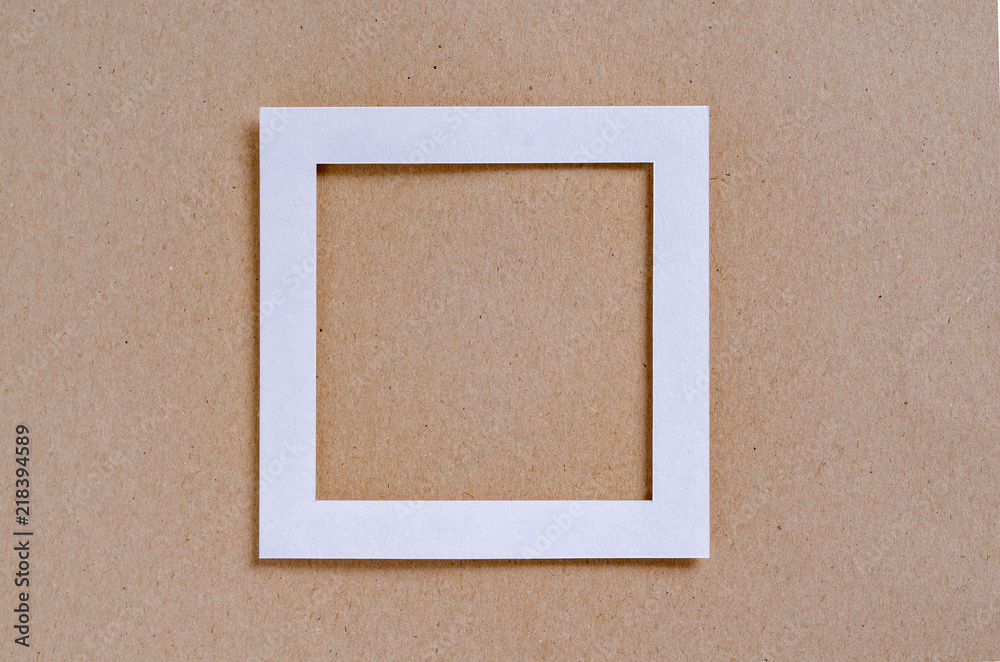 Fototapeta premium Empty white frame on a textured paper background, top view. Flat lay