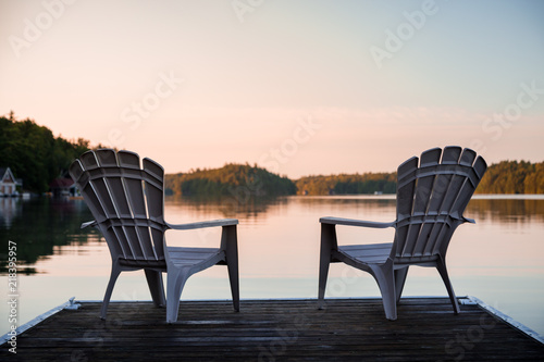 Muskoka chairs sitting at the end of a dock in front of Lake Joseph at sunrise. photo