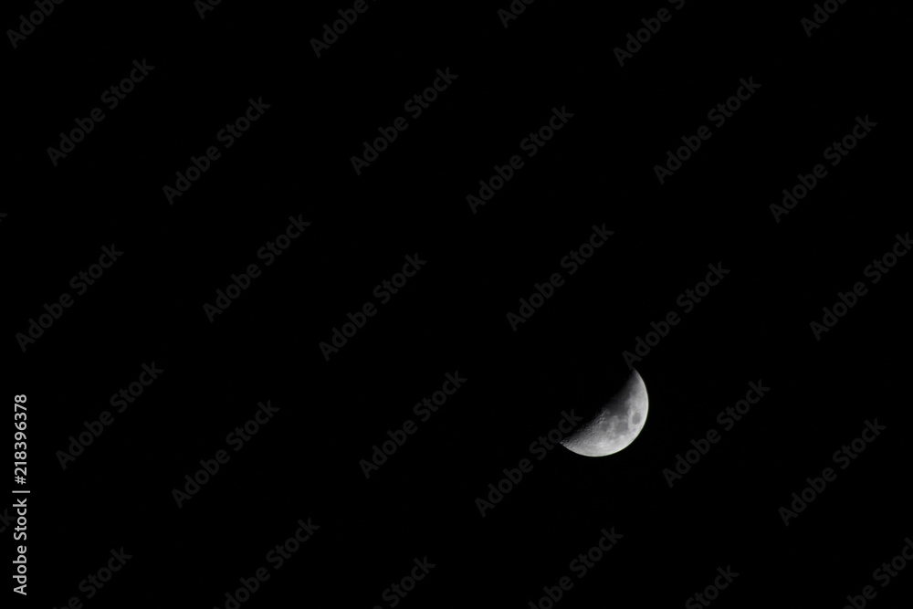 Crescent moon in the dark night with visible craters