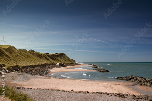 View of the danish beach coastline with green grass dunes during bright daytime and blue sky perfect for summer. Danish Beach, Lokken, Lønstrup in North Jutland in Denmark, Skagerrak, North Sea