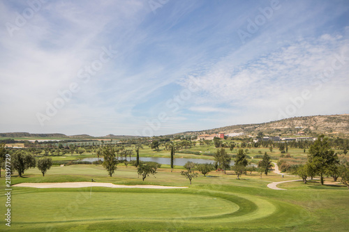 Golf course hole and flag with lake  trees and clubhouse in the background on a summer day