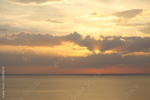Beautiful sunset with clouds of orange and yellow in the ocean, the river © Misha