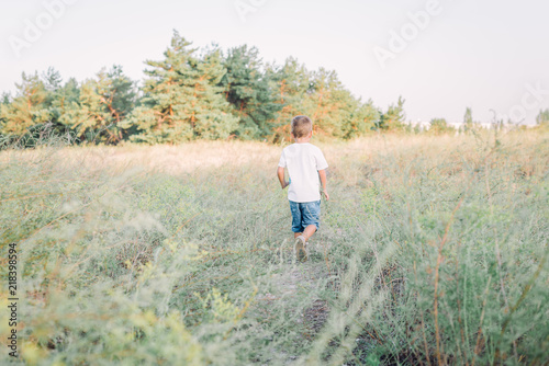 Little boy is walking on the countryside road on sunset © Ira_Shpiller