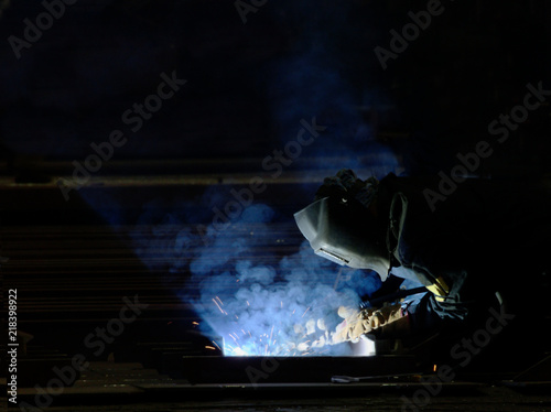 Worker welding production at an industrial plant in the smoke. side view