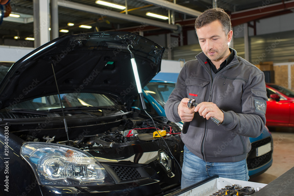handsome mechanic fixing a car engine in his garage handsome mechanic fixing a car engine in his garage