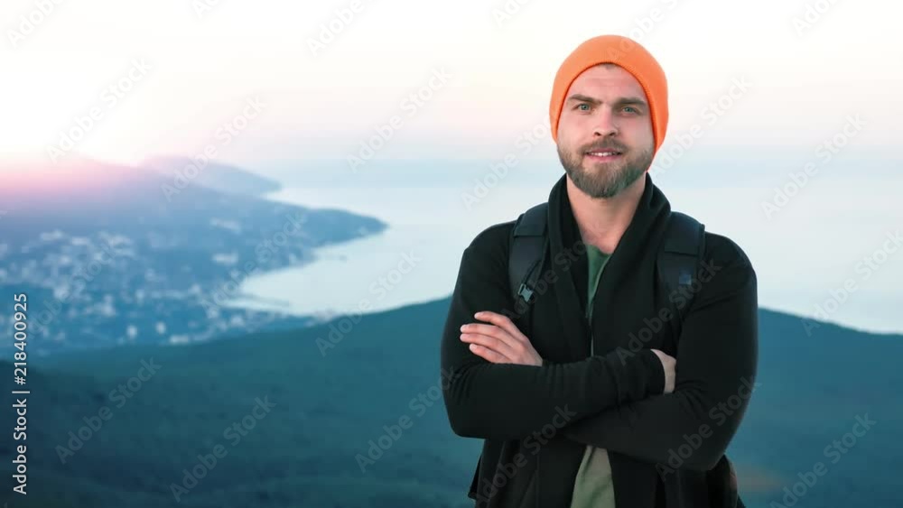Portrait European friendly hipster man standing on mountain top at sunset Portrait European friendly hipster man standing on mountain top at sunset
