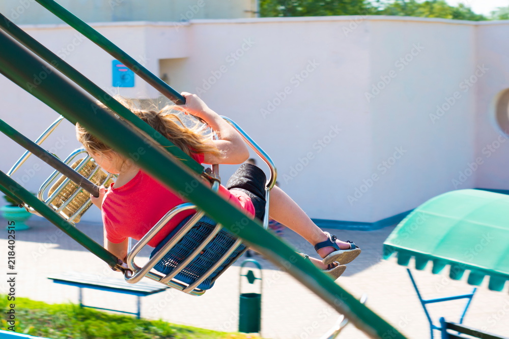 The girl is riding a carousel at high speed on a swing.