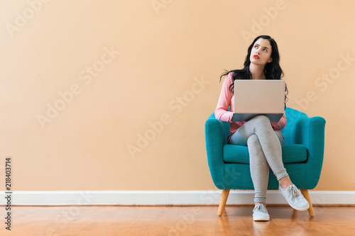 Young woman using her laptop on a blue chair