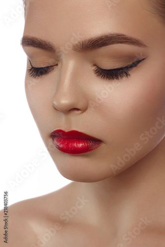 Beauty woman Face. Portrait of beautiful sexy young female with perfect matte facial makeup. Soft healthy skin. Glamorous girl on gray background. Red lips