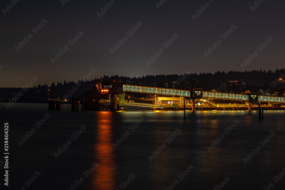 A long exposure of a ferry ramp at night with reflections in the water below