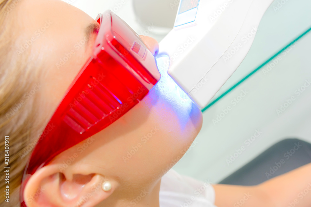 Naklejka premium Young woman having her teeth laser whitened