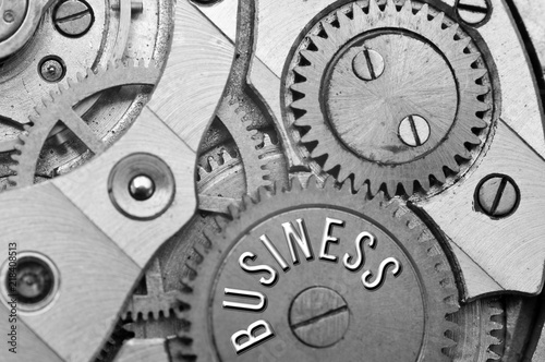 Background with the inscription BUSINESS. Black white background with metal cogwheels clockwork. Macro. 