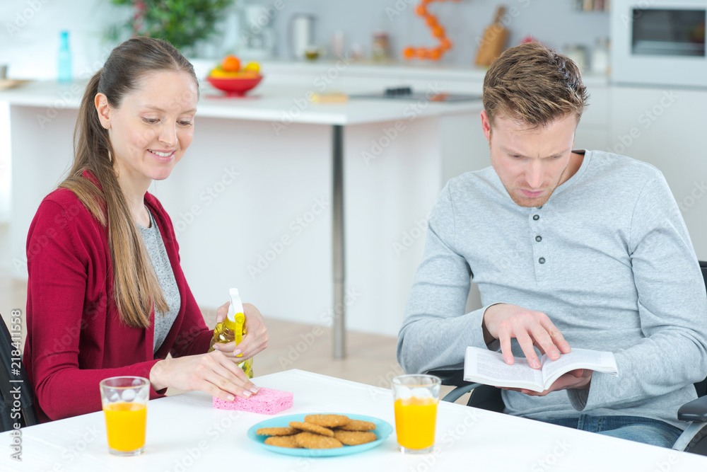 young couple reading book while having breakfast in kitchen