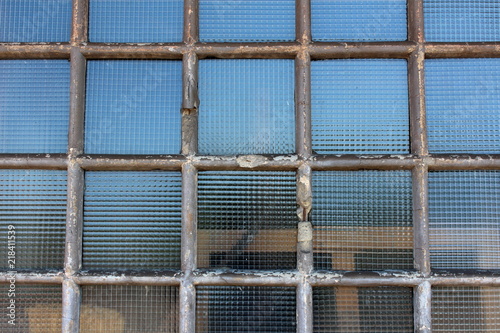 Safety wire protection glass windows with dilapidated concrete frames reinforced with metal wire on old warehouse with wooden palette in background