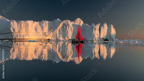 Greenland midnight Sunset iceberg mirror panorama with red sail ship 