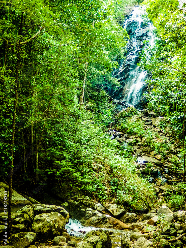Jungle stream flowing into waterfalls & pools, with surrounding rain forest and large rocks. Taken on a bright day at Paeng Waterfall, Ko Pha Ngan, Thailand. Jungle stream flowing into waterfalls & pools, with surrounding rain forest and large rocks. Taken on a bright day at Paeng Waterfall, Ko Pha Ngan, Thailand.