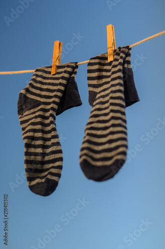 Pair of striped socks hanging on a clothesline against a blue sky background.