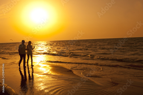 Romantic couple walking in the seaside in the sunset