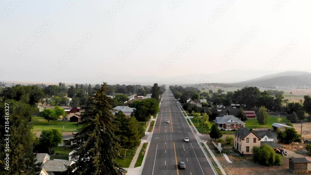 Aerial-Flying over Main Street with light traffic in a small rural mountain town in the golden morning light with smokey haze on the horizon from wildfires in the vicinity. Aerial-Flying over Main Street with light traffic in a small rural mountain town in the golden morning light with smokey haze on the horizon from wildfires in the vicinity.