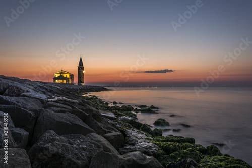 Enlightened church and tower "Santuario della Madonna dell'Angelo" in the town of Caorle on the coast. Dawn. Lighting beacon. © Petr