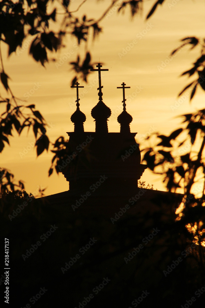 The silhouette of cupolas of Wooden Saint George Church in Kolomenskoe against bright sunset sky