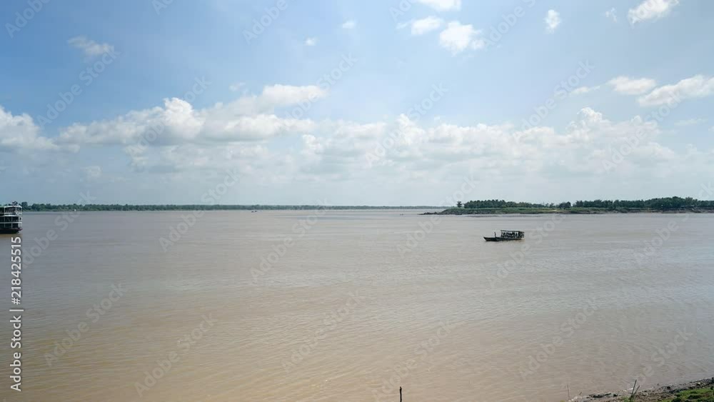 Distance view of a cruise ship on river getting closer to the riverbank; Ferry boat crossing the river in the foreground Distance view of a cruise ship on river getting closer to the riverbank; Ferry boat crossing the river in the foreground