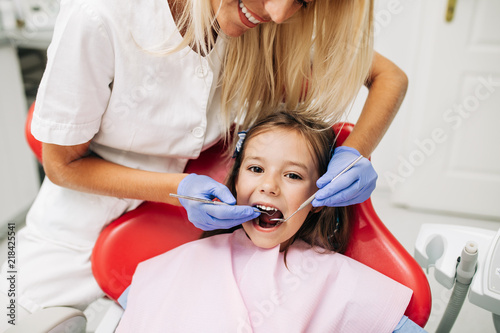 Cute little girl sitting on dental chair and having dental treatment.