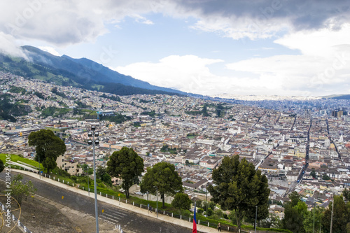 A panoramic view from higher ground of the city of Quito, capital of Ecuador. Buildings, houses and the mountains can be seen in the back. It's a sunny day with blue sky. photo taken from El Panecillo