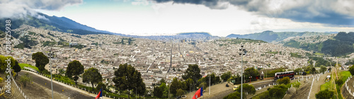 A panoramic view from higher ground of the city of Quito, capital of Ecuador. Buildings, houses and the mountains can be seen in the back. It's a sunny day with blue sky. photo taken from El Panecillo